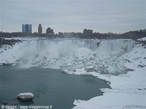 Frozen Niagara Falls, ice blocks below the cascades and skyscrapers behind