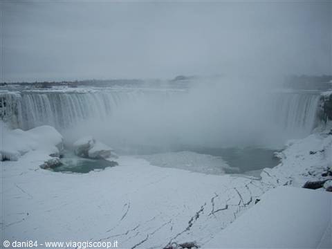 Frozen Niagara Falls under snow, mist rising above the falls