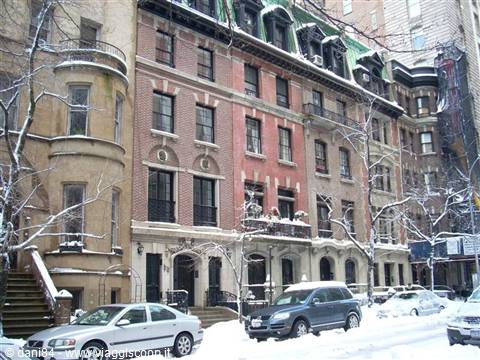 Snow-covered brick rowhouses with parked cars in Manhattan