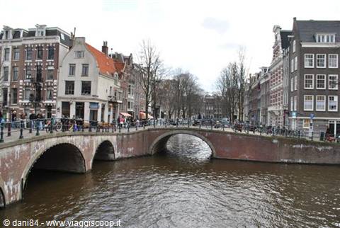 Brick bridge over Amsterdam canal among tall Dutch gabled houses