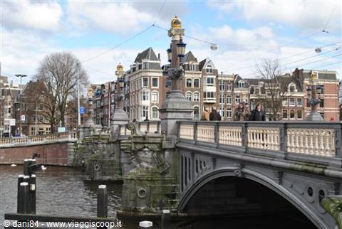 Tourists on the Blauwbrug bridge in Amsterdam among Dutch houses and canal