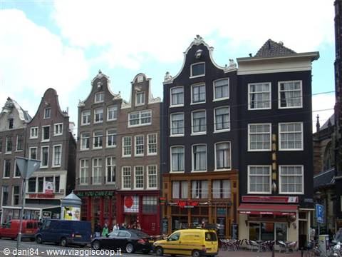 Traditional Dutch gabled houses in Amsterdam, with cafes and yellow vans below