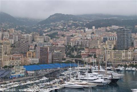 Yachts moored at Monaco's Port Hercule, buildings under low fog