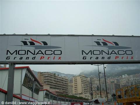 Monaco Grand Prix sign above grandstands, buildings and hills under grey sky