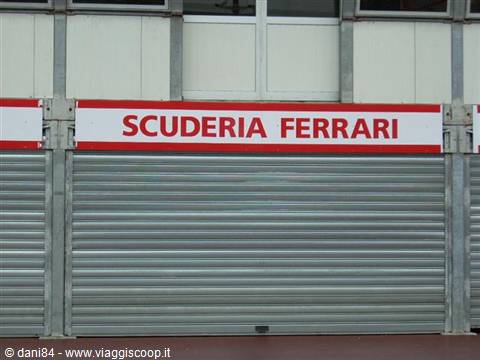 Red Scuderia Ferrari sign above closed metal shutters