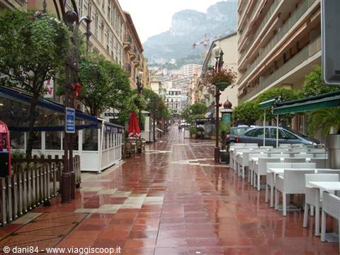 Wet street in Monte Carlo with café tables and mountain in the background
