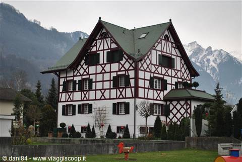 Half-timbered house with red beams in front of snowy mountains
