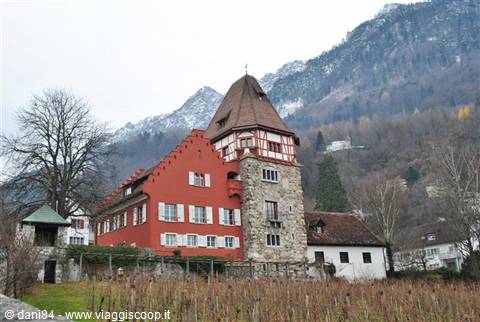 The Red House in Vaduz, red plastered walls and stone tower, among vineyards and snowy mountains