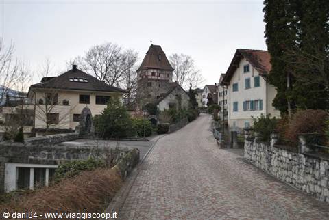 Cobblestone street climbing toward medieval tower among traditional houses