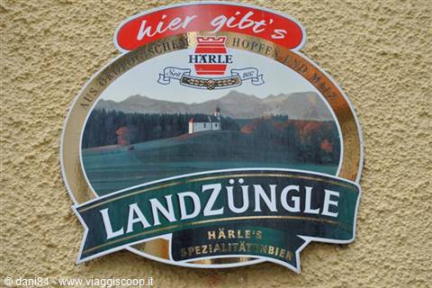 Harle LandZüngle metal sign with painted church and mountains on yellow plastered wall