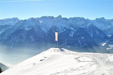 Red flag on snowy summit, stylized pixel art, alpine mountains in background