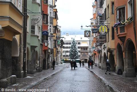 Pedestrian street in Innsbruck with snowy Christmas tree among colorful buildings