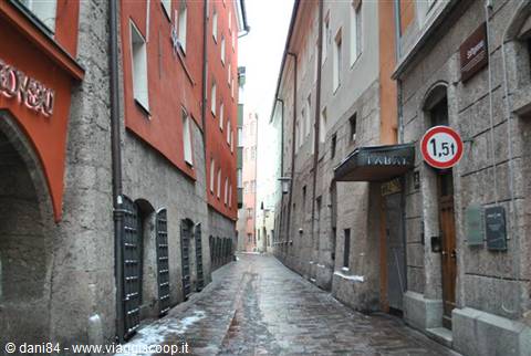 cobbled alley between stone buildings, pizzeria sign and traffic sign
