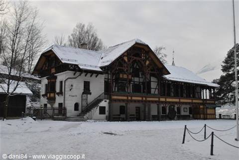 Snow-covered railway station with wooden roof under grey sky