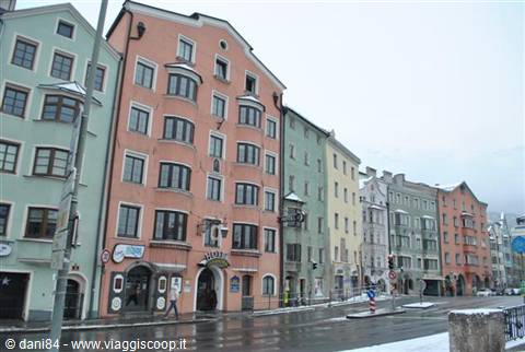 Pastel-colored buildings along a wet street, winter in Innsbruck