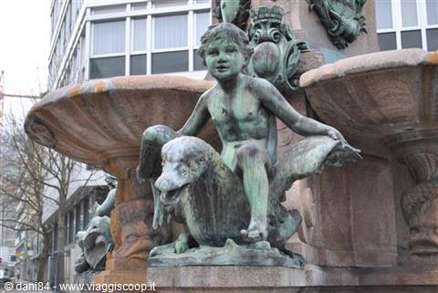 Bronze statue of a boy sitting on a dolphin in a city fountain