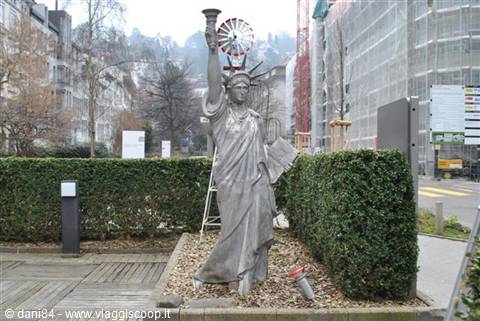 Metal Statue of Liberty replica between hedges, scaffolding and bare trees