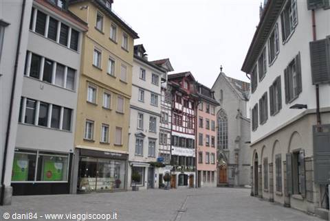 Square with colorful houses and timber-framed facade, Gothic church in background