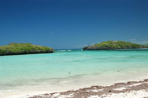 white sand beach, turquoise water and green hills under blue sky