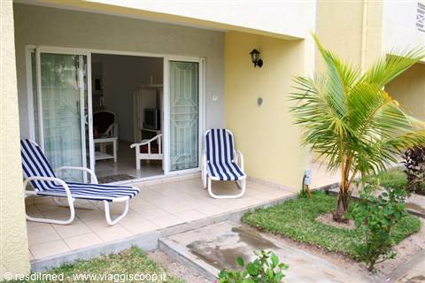 Residence porch with two blue striped loungers, sliding glass doors and palm