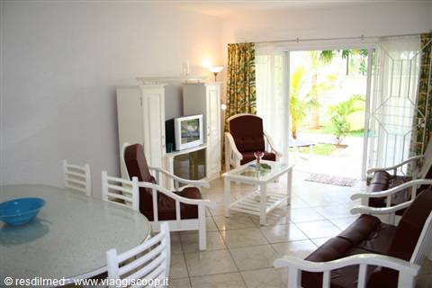 Living room with white wooden furniture and open door onto tropical garden