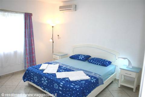 Hotel bedroom with blue double bed, air conditioning and warm lamp light