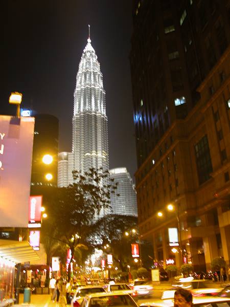 The illuminated Petronas Towers at night above Kuala Lumpur traffic