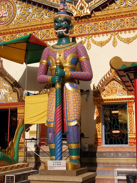 Painted guardian statue holding a sword in front of Wat Chetawan temple