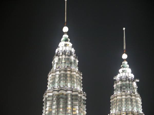 The Petronas Towers lit up at night in Kuala Lumpur, gleaming steel and glass