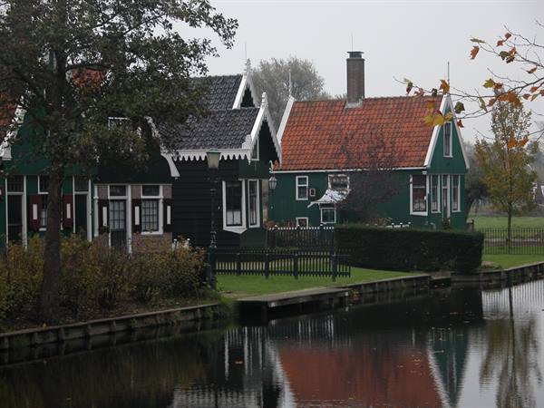 Green wooden houses with red tile roofs reflected in the canal, Zaanse Schans
