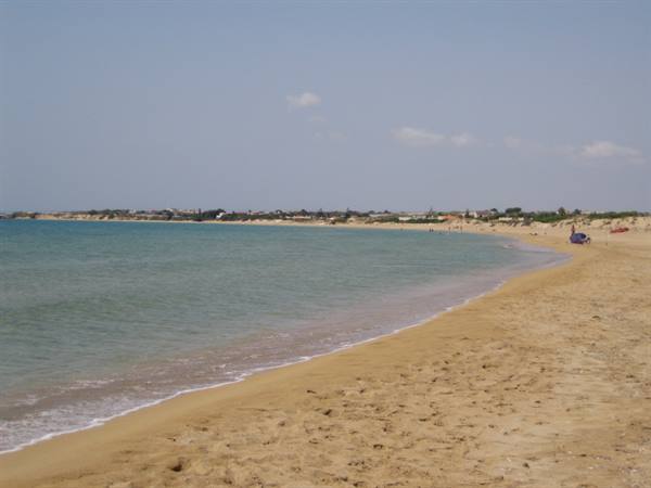 Golden sand and turquoise sea with beachgoers under a summer sky