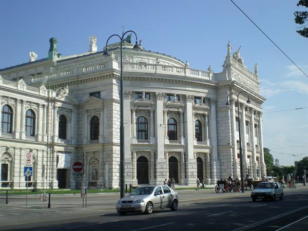 Vienna's Burgtheater, white facade in sunlight, cars and carriages on Ringstrasse