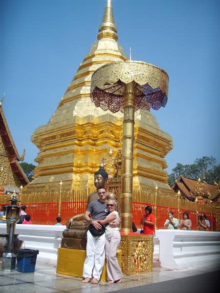 Couple beside golden Buddha and chedi at Wat Phra That Doi Suthep, Chiang Mai