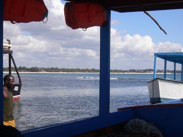 Red life vests hanging on a blue boat facing the beach
