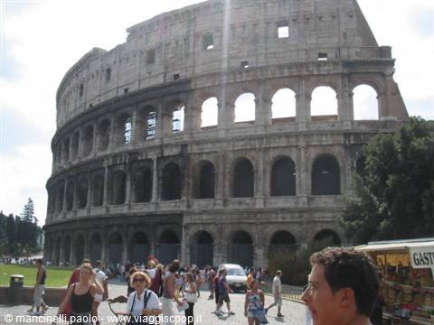 Tourists walk in front of the Colosseum in Rome on a sunny day