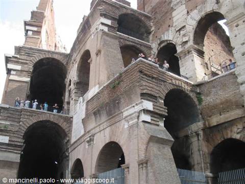 Tourists on the inner walkways of the Colosseum among brick and stone arches