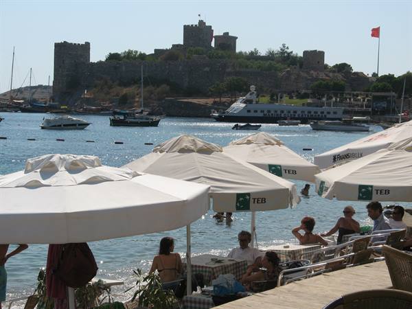 Beach umbrellas and swimmers in front of Bodrum Castle by the sea