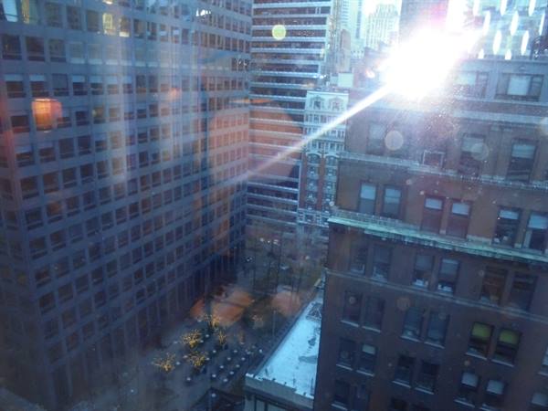 Manhattan skyscrapers seen through a window, sunlight reflecting on the glass