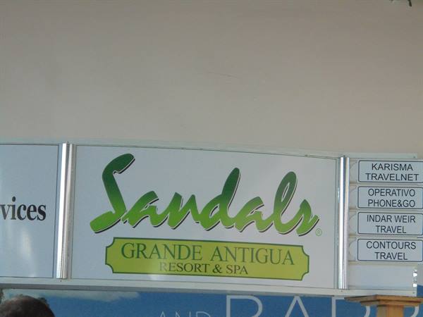 Green Sandals Grande Antigua Resort sign next to travel agency panels