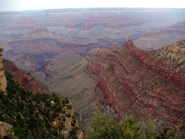 Grand Canyon: layered red rock cliffs under a hazy sky
