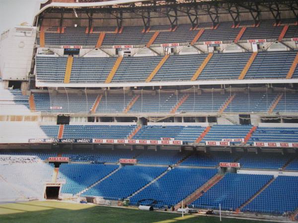 Santiago Bernabéu stadium, empty blue stands and green pitch in daylight