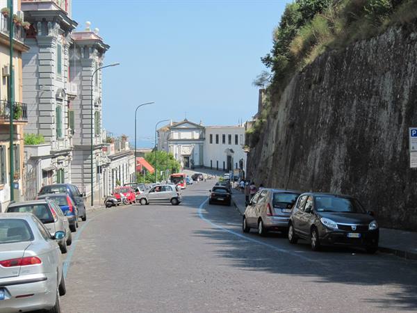 Uphill street with parked cars, historic buildings and a white church ahead