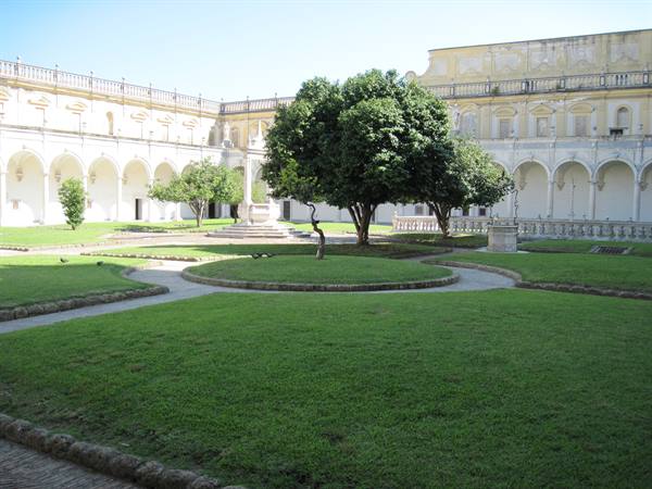 Great cloister of Certosa di San Martino in Naples, lawns and trees among white arcades