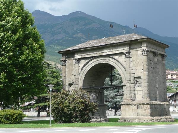 Arch of Augustus in Aosta, ancient stone, mountains and dark clouds behind