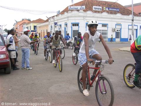 Young cyclists ride down the street past shops in colonial buildings