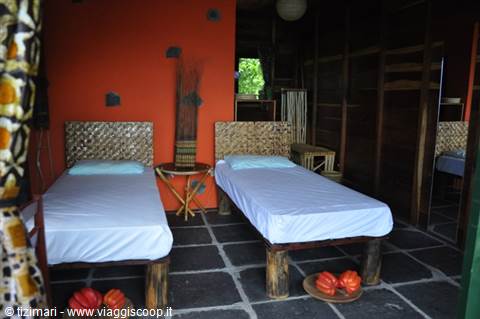 Room with two wooden beds, orange wall and black stone floor