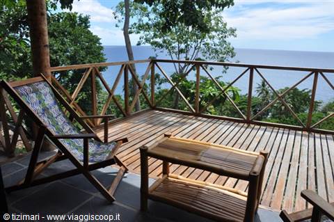 Wooden terrace with deck chair and table, overlooking the tropical sea