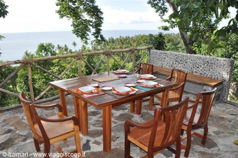Wooden dining table set on stone terrace above the sea