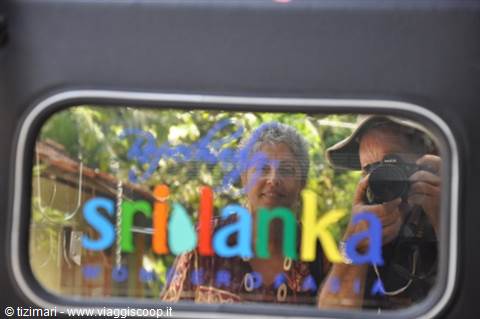 Reflections on the train window: photographer with camera and colorful Sri Lanka sign