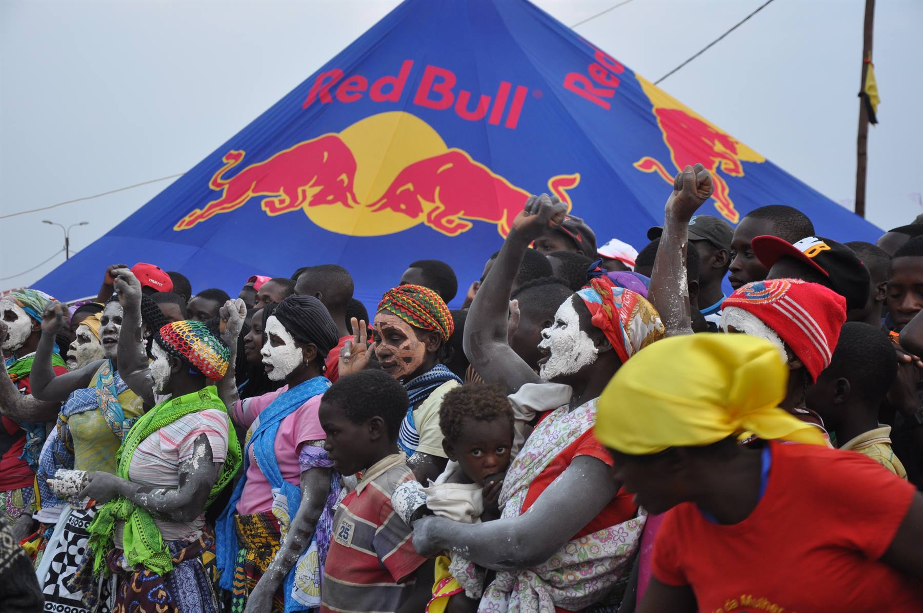 Donne col volto bianco ballano davanti a una tenda gigante Red Bull